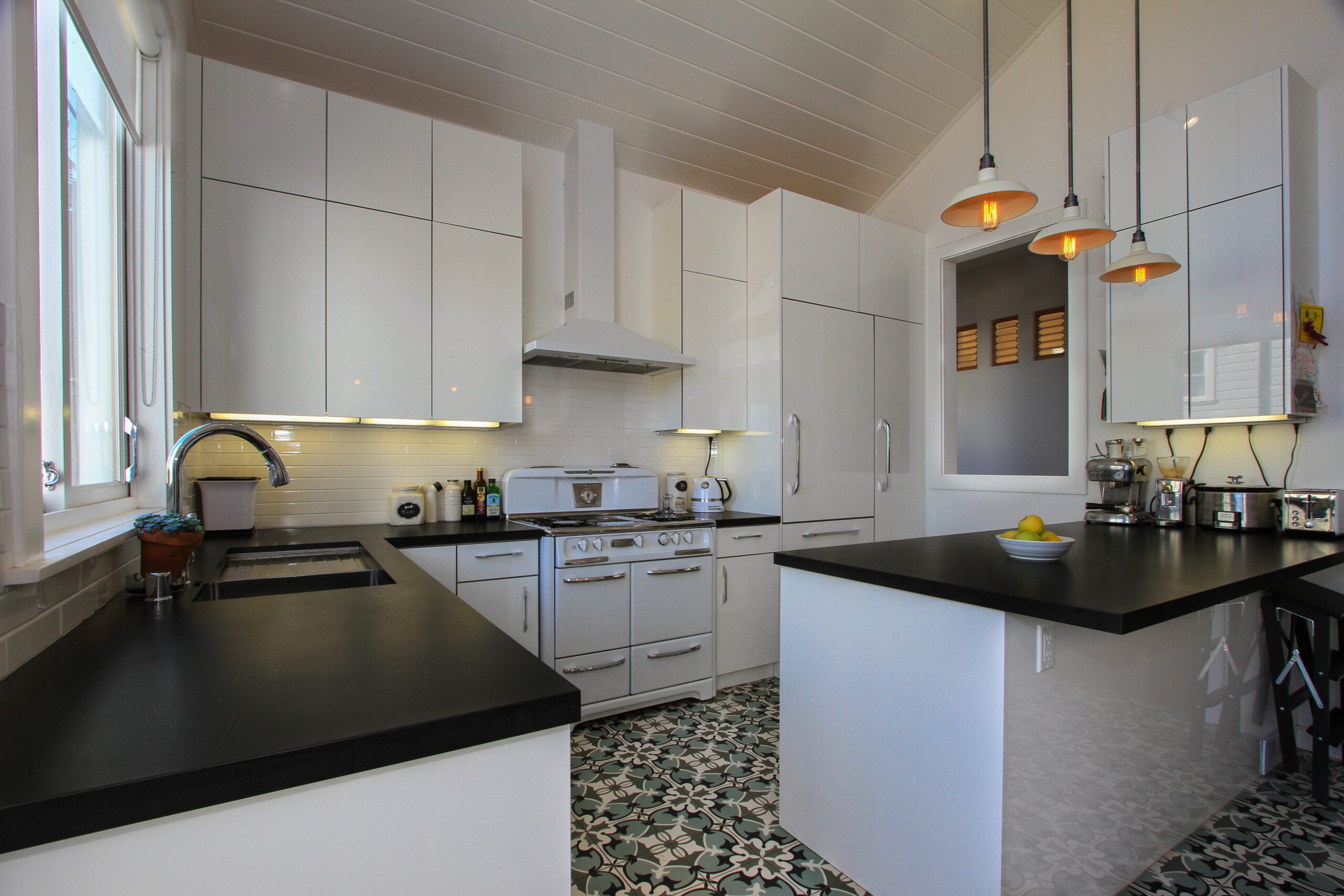 Modern kitchen with white cabinetry, black countertops, and patterned floor tiles.