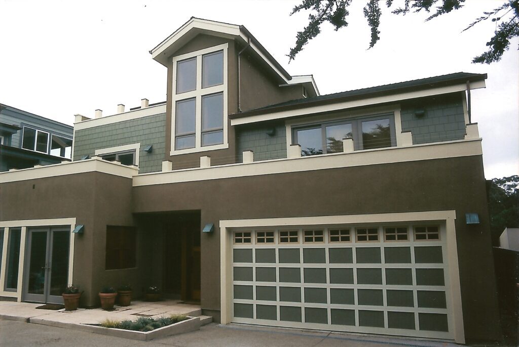 Modern two-story house with a large garage door and a combination of stucco and wood siding.