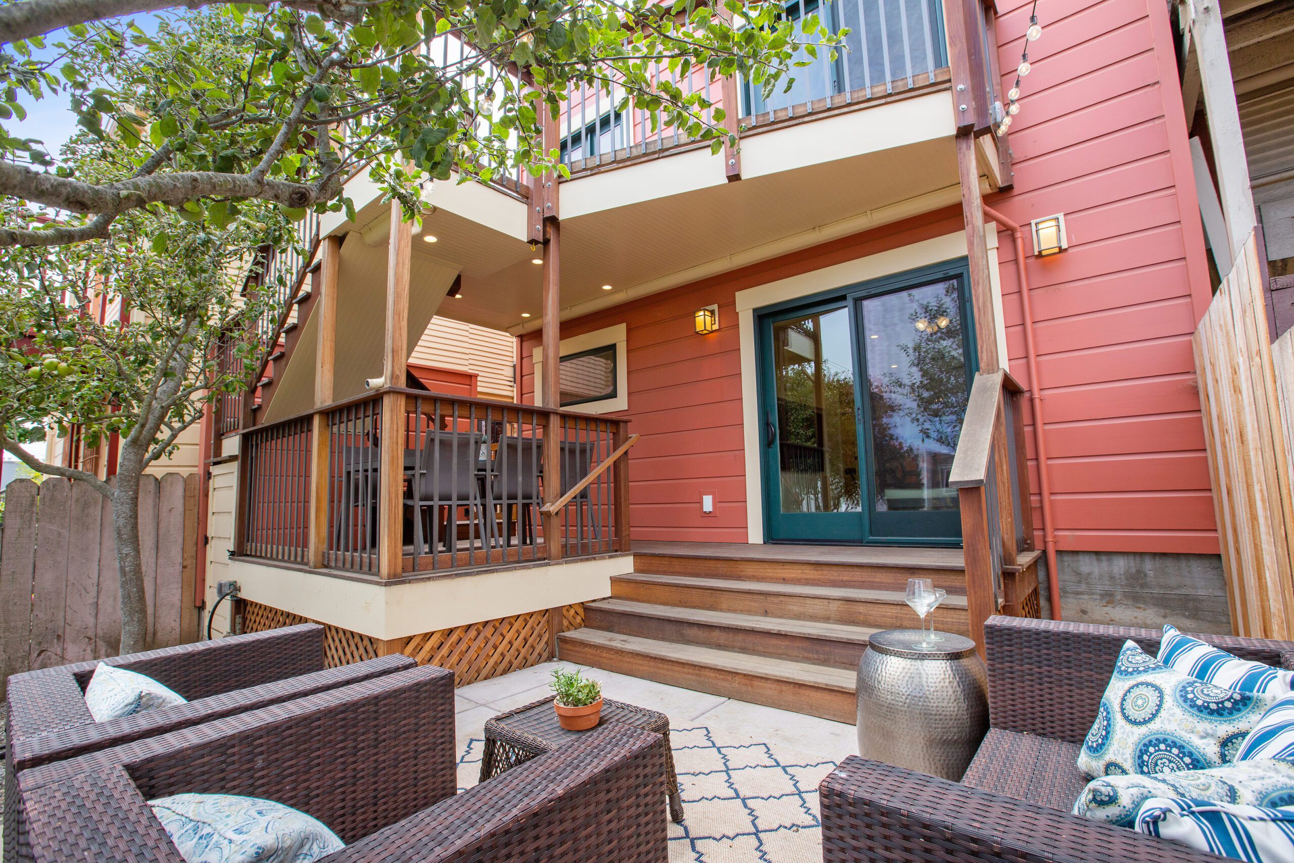 Comfortable outdoor seating area in front of a modern house with a red facade and a small, inviting porch.