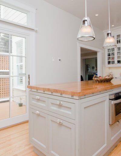 Bright, modern kitchen with an island, stainless steel appliances, and glass doors leading to an outdoor deck.