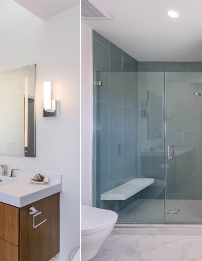 Modern bathroom with a wooden vanity, wall-mounted lights, large mirror, and a glass-enclosed shower with a built-in bench and blue tiles.